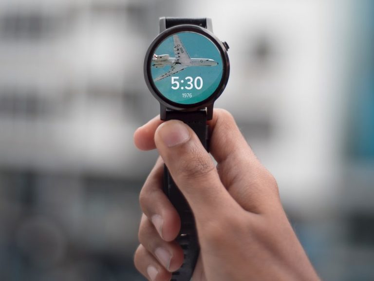 selective focus photography of person holding black smartwatch displaying 5:30