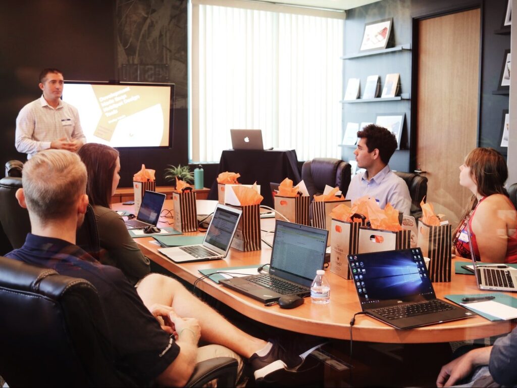 man standing in front of people sitting beside table with laptop computers