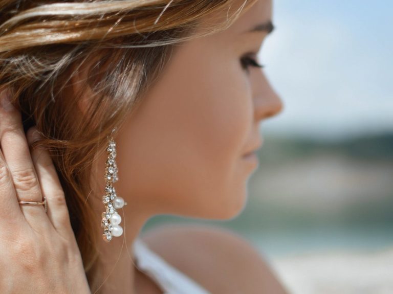 shallow focus photography of woman wearing dangling earrings holding her hair near mountain
