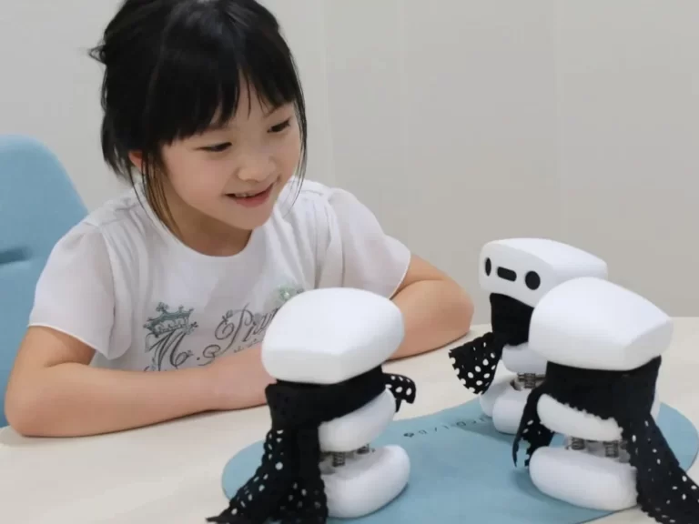 a young girl looks at a cluster of three simple robots facing each other on a table e
