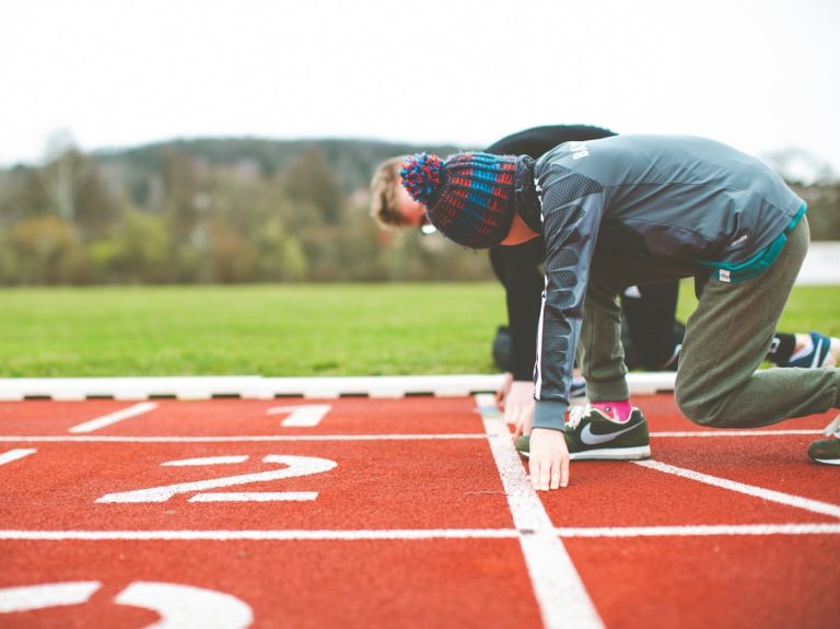 man in black and red plaid shirt and black pants standing on track field during daytime