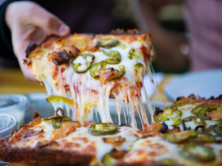 a person taking a slice of pizza from a plate
