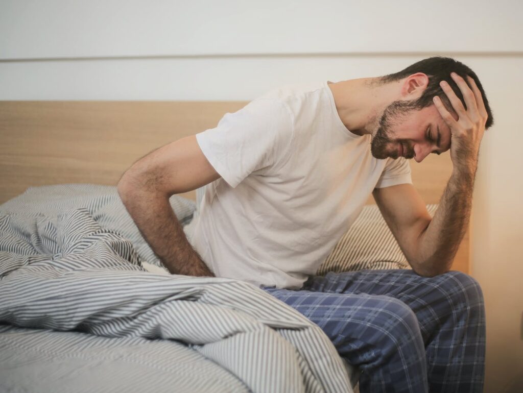 Young man in sleepwear suffering from headache in morning