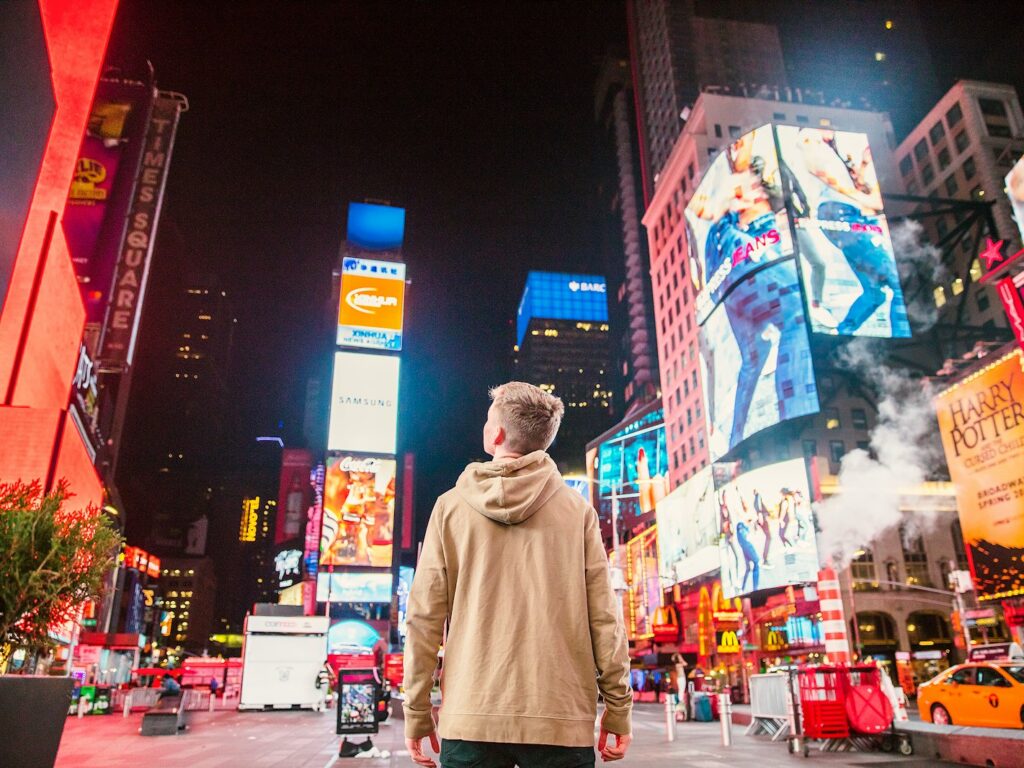 man standing on road infront of high-rise buildi