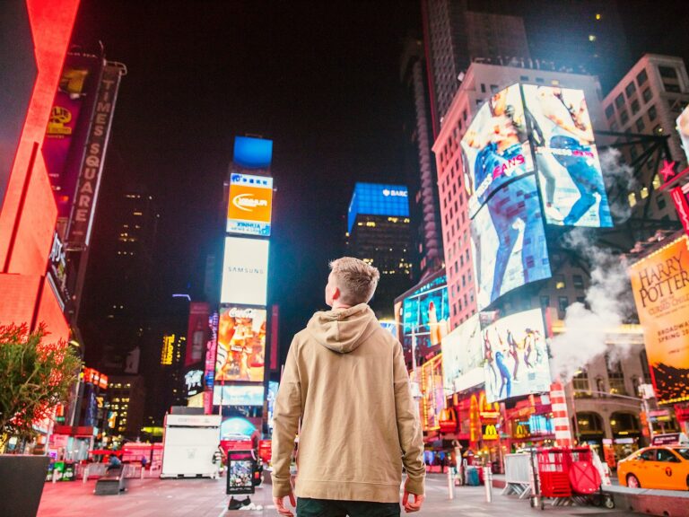 man standing on road infront of high-rise buildi